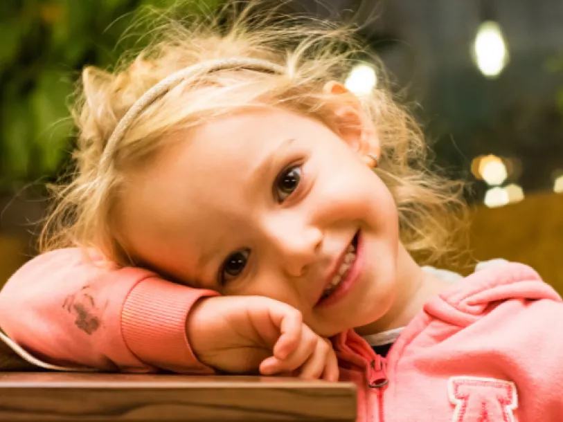 Young girl smiling with head resting on her arm